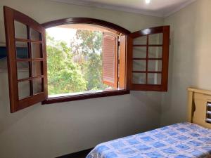 a bedroom with a bed and an open window at Casa grande, ampla, com 4 quartos e estacionamento in Ribeirão Preto