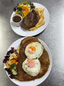 two plates of food with eggs and fries on a table at Kaponga Hotel in Kaponga