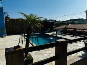 a swimming pool with a palm tree in a yard at Chacara com Piscina em Suzano completa in Suzano