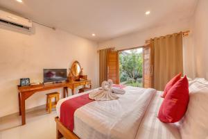 ein Schlafzimmer mit einem Bett, einem Schreibtisch und einem Fernseher in der Unterkunft Gati Cottage in Nusa Penida