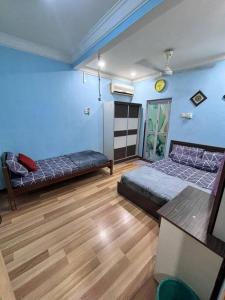 a bedroom with two beds and a wooden floor at Kurma & Manggis Homestay 5BR in Paya Rumput