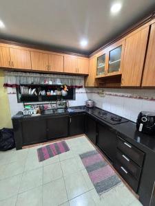 a kitchen with black counters and wooden cabinets at Kurma & Manggis Homestay 5BR in Paya Rumput +8 photos