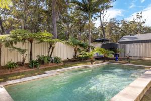 a swimming pool in a yard with a fence and trees at The Atrium by Experience Jervis Bay in St Georges Basin