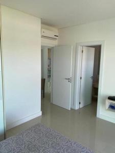 a room with white walls and a hallway with doors at Casa de Luxo no Condomínio Enseada in Xangri-lá