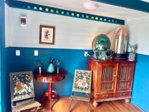 a room with a blue wall and a table and a clock at Mælstrøm End Eco Farmstay in Puponga