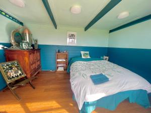 a blue bedroom with a bed and a wooden floor at Mælstrøm End Eco Farmstay in Puponga