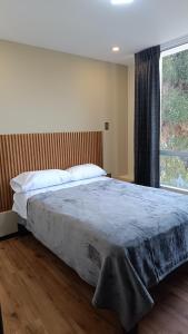 a bed in a bedroom with a large window at APARMENTS Av LA PAZ in Arequipa