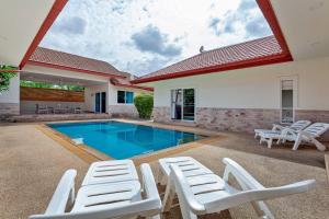 a house with a swimming pool and white lounge chairs at Beautiful 5 Bedroom Luxury Pool Villa in Pattaya in Ban Huai Yai