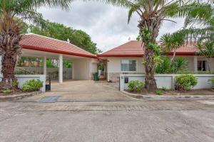 a house with palm trees in front of it at Beautiful 5 Bedroom Luxury Pool Villa in Pattaya in Ban Huai Yai