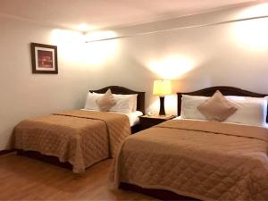 a hotel room with two beds and a lamp at Casa Cecilia Heritage Hotel in Taal