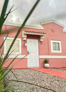 une maison rose avec une porte blanche devant dans l'établissement Casa Décima - Recién Remodelada, à Hermosillo