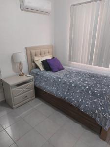 ein Schlafzimmer mit einem Bett, einem Nachttisch und einem Fenster in der Unterkunft Hermoso departamento con alberca in La Sabana