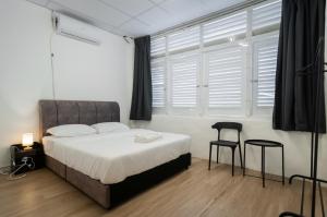 een slaapkamer met een bed en twee stoelen en een raam bij The Terraces by Aayu - 2 mins walk to Chulia Street in George Town