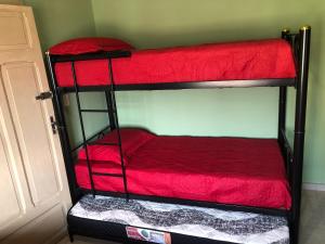 two bunk beds in a room with red sheets at CASA EM BH Santa Efigênia in Belo Horizonte
