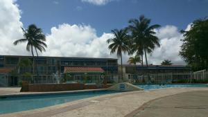 a building with a swimming pool and palm trees at Deluxe Beach Condo in Dorado in Dorado