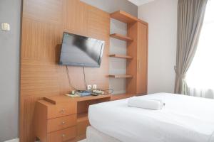 ジャカルタにあるComfort and Simply Look 1BR at Bellezza Apartment By Travelioのベッドと壁掛けテレビのある寝室