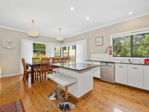 a kitchen with white cabinets and a table and chairs at Scenic Cottage in Katoomba