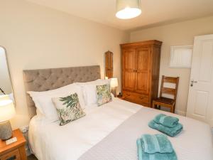 a bedroom with a large white bed with towels on it at Crossing Cottage in Whitby