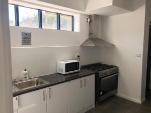 a small kitchen with a sink and a microwave at St Kilda Accommodation in Melbourne