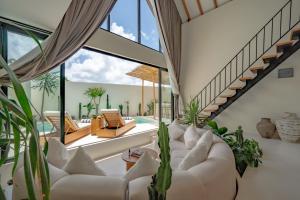 een woonkamer met witte meubels en planten bij 7Seas Bingin in Uluwatu