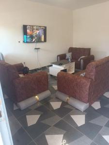 Una sala de estar con dos sillas y un televisor. en Résidence Meublée Smart 2, en Man