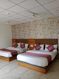 拉杰果德Hotel Rudraksh的砖墙客房内的两张床 更多20张照片