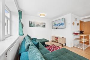 a living room with a green couch and a table at Apartments am Hainich - 6 Personen, King-Size-Betten, Netflix, Nationalpark in Hörselberg-Hainich