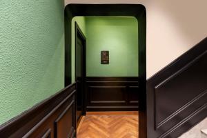 a hallway with a green wall and a door at Kudos-My Downtown Hotel in Udaipur