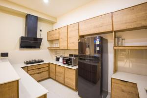 a kitchen with a black refrigerator and wooden cabinets at ELIVAAS Signature 4 BHK with Balcony & Terrace - Antarmann Casa Nova in Bhīm Tāl