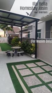 a patio with two benches and a table in front of a house at illa Bella Homestay Jasin in Jasin