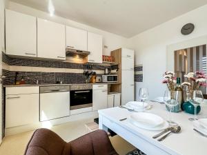 ヴォルフスブルクにあるR und S Apartments Stylische Wohnung I Küche I Parkplatz I Smart TVの白いキャビネット、白いテーブルと椅子付きのキッチン