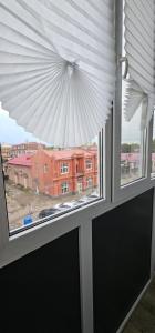 una ventana con vistas a un edificio de ladrillo rojo en LUX-Апартаменты New York style на Чехова, en Öskemen