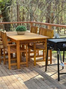 a wooden table and chairs on a patio with a grill at Greenwood Cottages in Tolmie