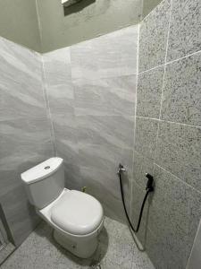 a bathroom with a toilet in a tiled wall at Casaria Beach in Paka