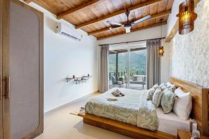 a bedroom with a bed and a large window at ELIVAAS 2 BHK With Balcony & Hill Lake - Antarmann Casa Ember in Bhīm Tāl