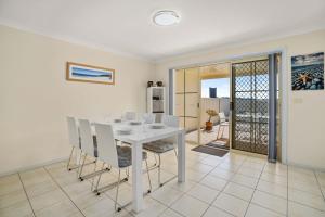 a white dining room with a white table and chairs at Pier 8 by Experience Jervis Bay in Huskisson