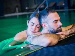 a man and a woman in a swimming pool at Euler Neuschönau - 4 Sterne Superior Hotel in Neuschönau