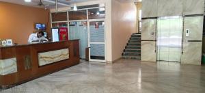 a lobby with a person at a counter and stairs at Grande Idhanta Hotel in Bellary