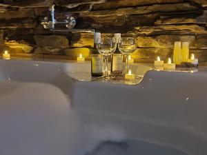 a bath tub with glasses of wine and candles at Stone Spa Apartman 2 in Sremčica