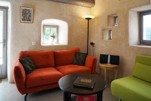 a living room with an orange couch and a table at Le Colombier Saint-Véran in La Roque-Sainte-Marguerite