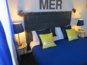 a bedroom with a bed with blue sheets and yellow pillows at Hôtel Les Embruns Sables d'Olonne in Les Sables-dʼOlonne