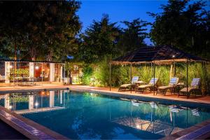 a swimming pool with chairs and a gazebo at Maa Ashapura Resort in Sawāi Mādhopur