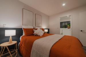 a bedroom with a large orange bed and a stool at Luxury Central City Getaway in Christchurch