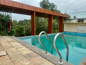 a swimming pool with two metal hand rails in it at Hotel Vrindavan Palace in Indore