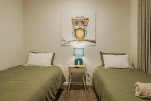 a bedroom with two beds and a table with a lamp at Elegant 3BR Home on Mustang Avenue in Christchurch