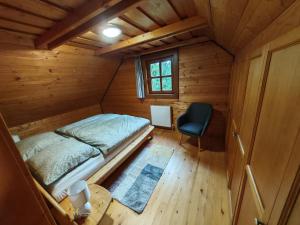 a bedroom in a wooden cabin with a bed and a chair at Chata KORSO v súkromí so záhradou 1200m2 in Terchová