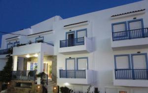 a white house with blue windows and balconies at night at Luis Apartments in Mastihari