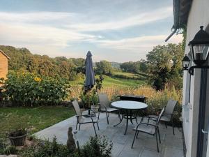 a patio with a table and chairs and an umbrella at Gite Happy Sun Flower in Virlet