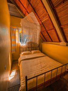 a bed in a room with a wooden ceiling at Sipi Falls Lodge in Sipi