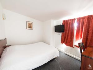 a small bedroom with a white bed and a television at Hotel La Basilique in Épinal